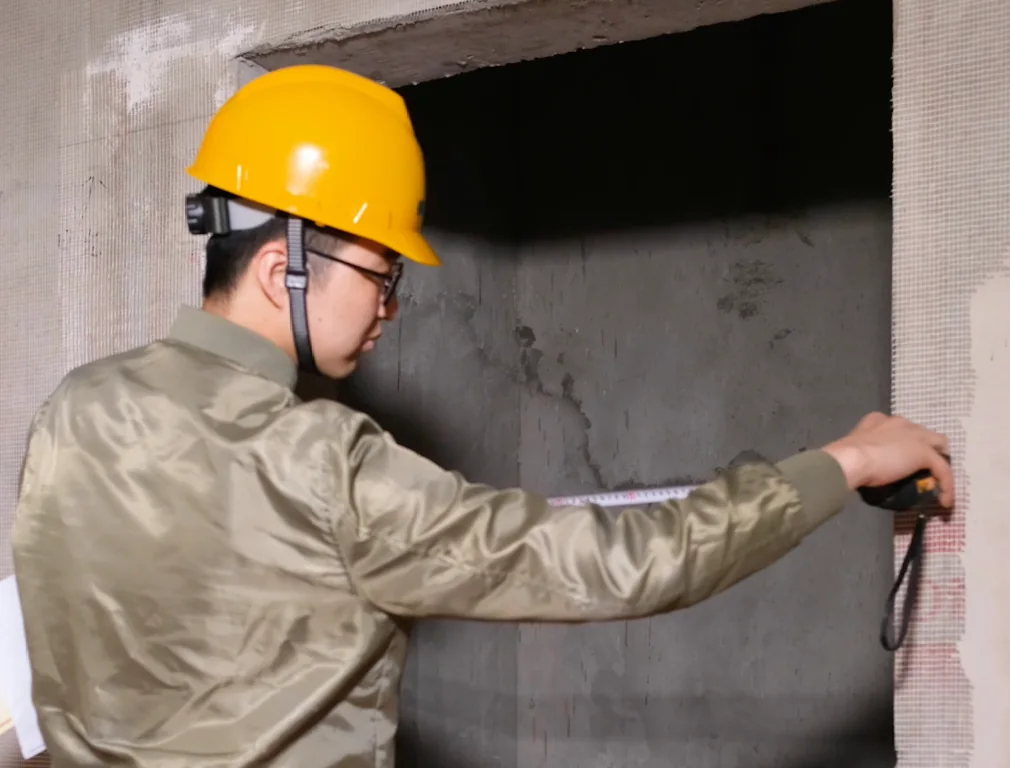 Worker measuring an unfinished elevator opening with a tape measure