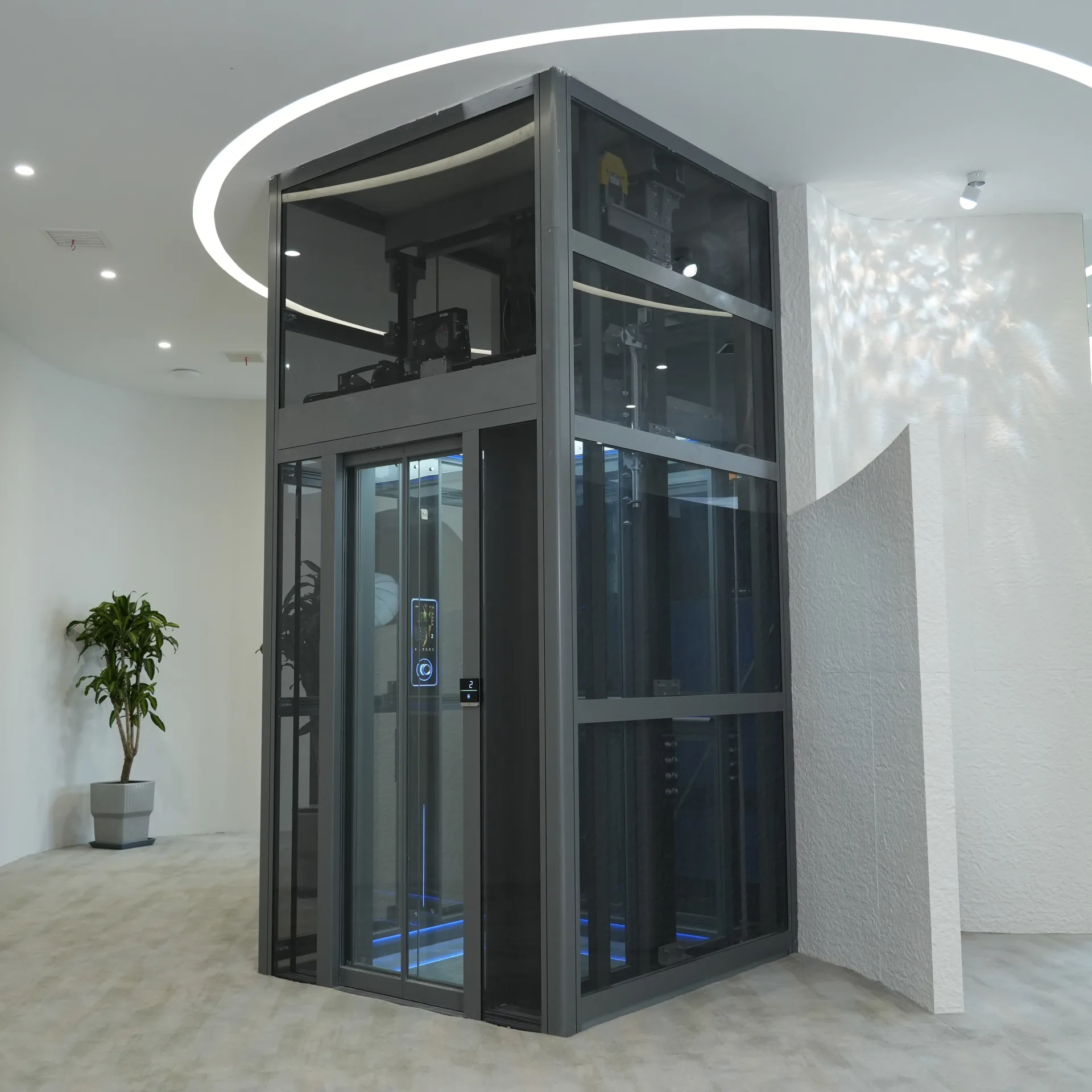 Blue-gray framed glass elevator tower beneath a circular ceiling opening in the showroom