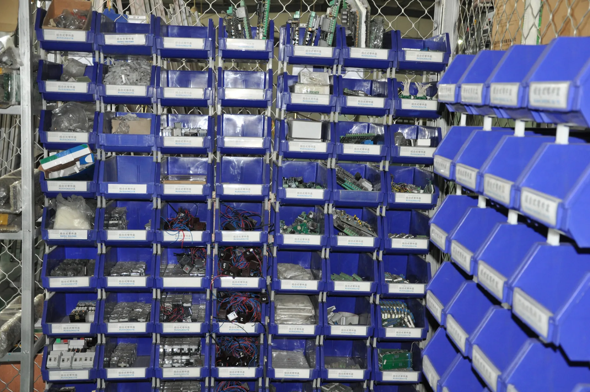 Labelled blue bins holding electrical parts, wiring and small components.