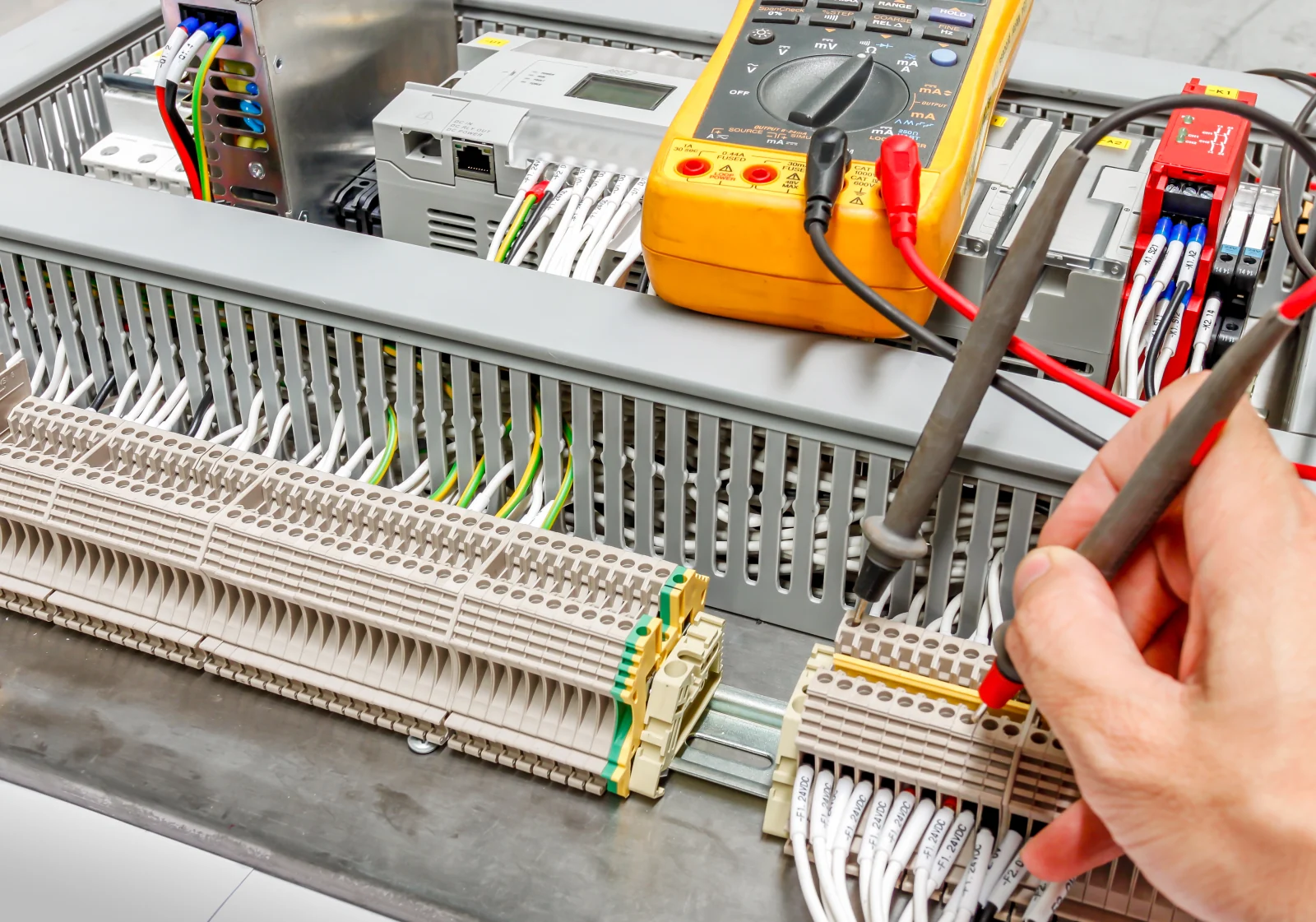 Testing terminals inside an electrical panel with a digital multimeter.