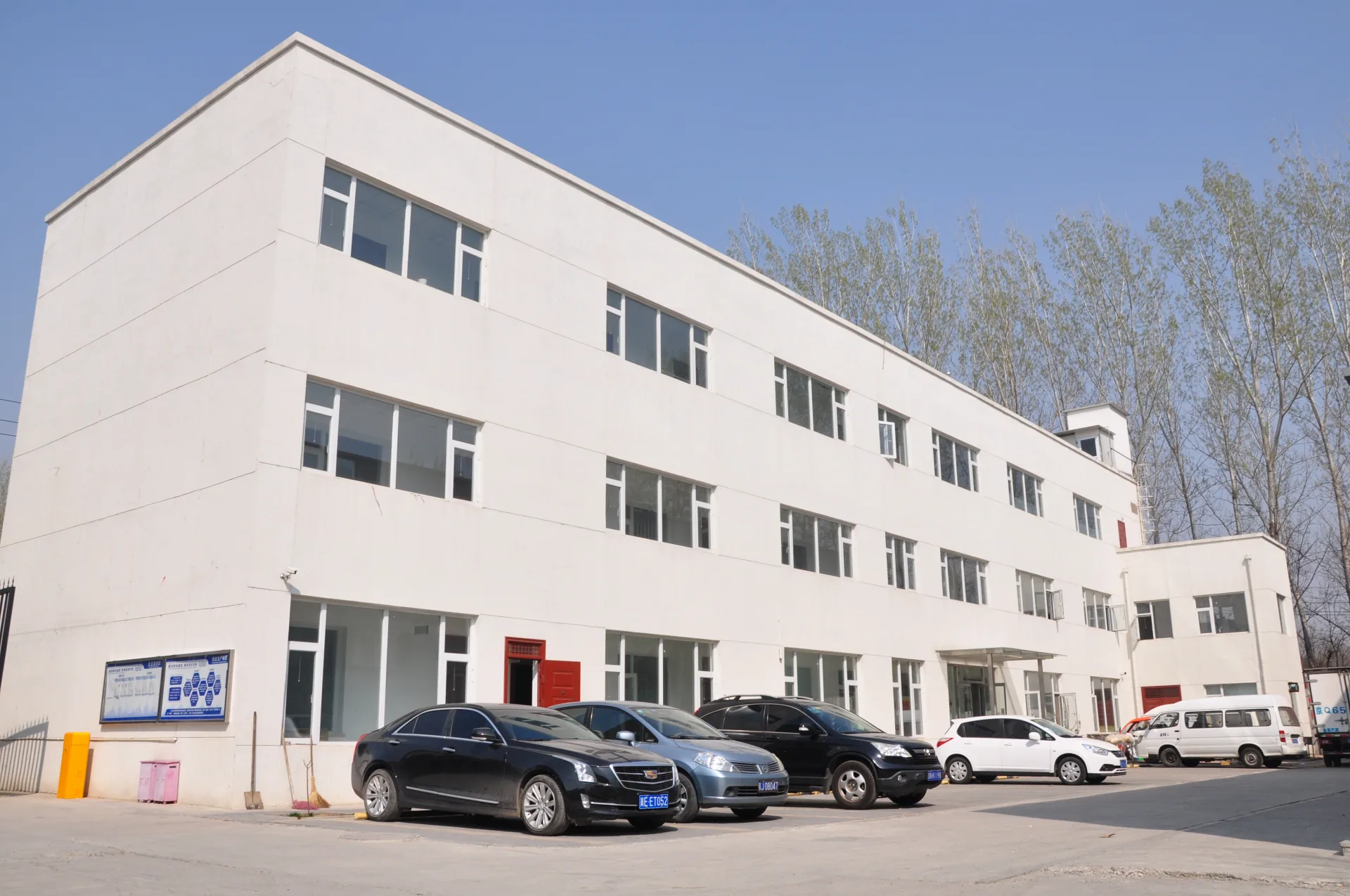 The exterior of a white workshop building with vehicles parked outside.