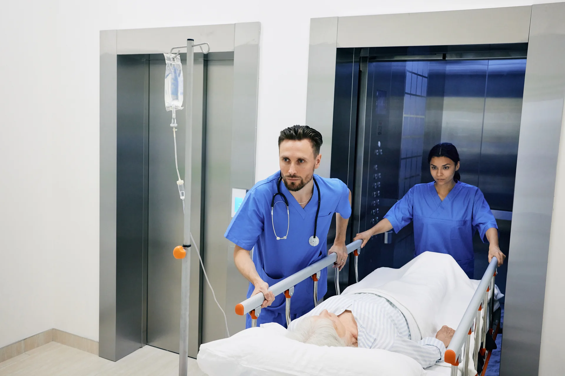 Clinical staff moving a hospital bed through an elevator entrance