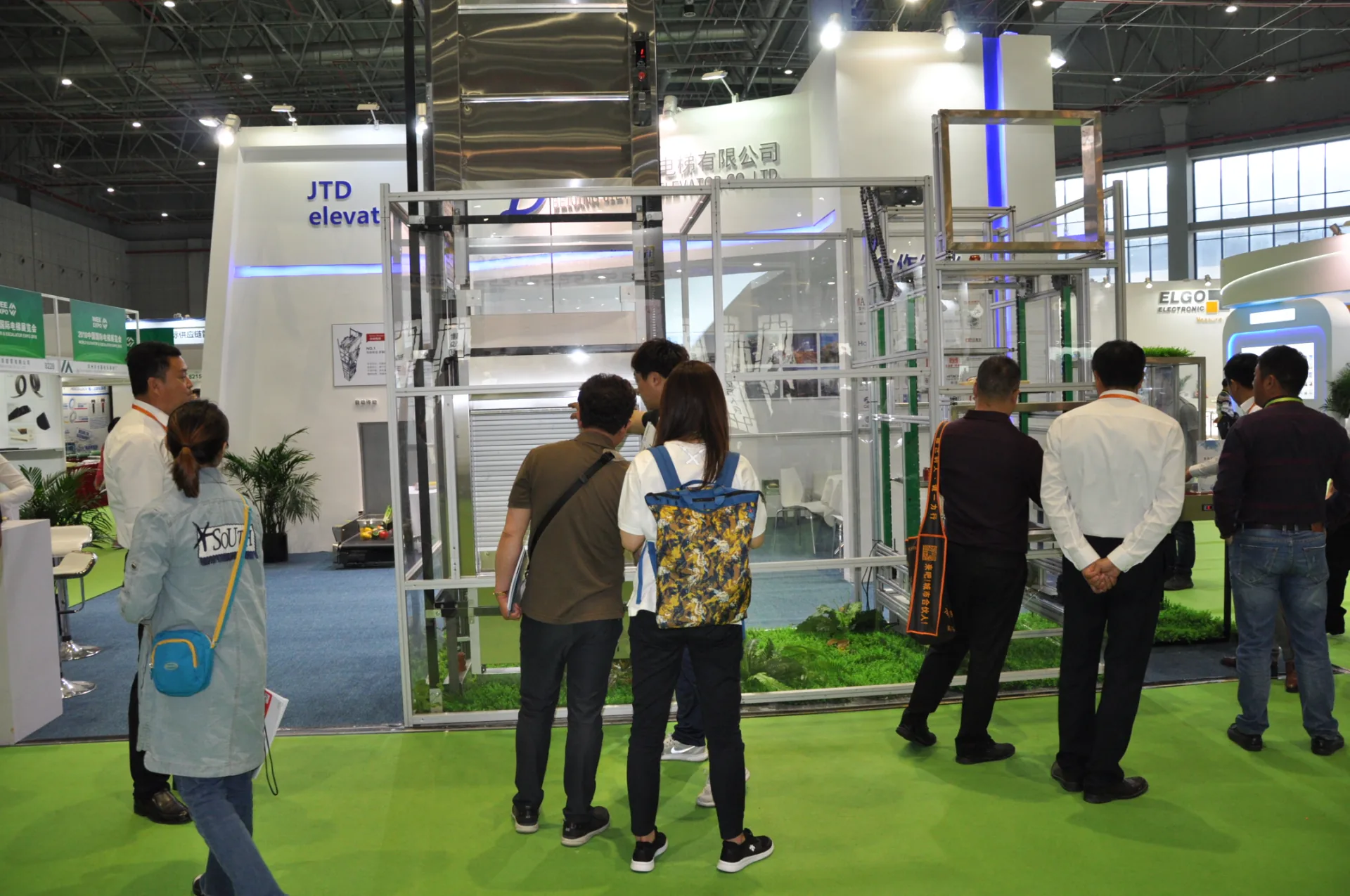 Visitors discussing a goods-lift demonstration at the Jieteda booth.