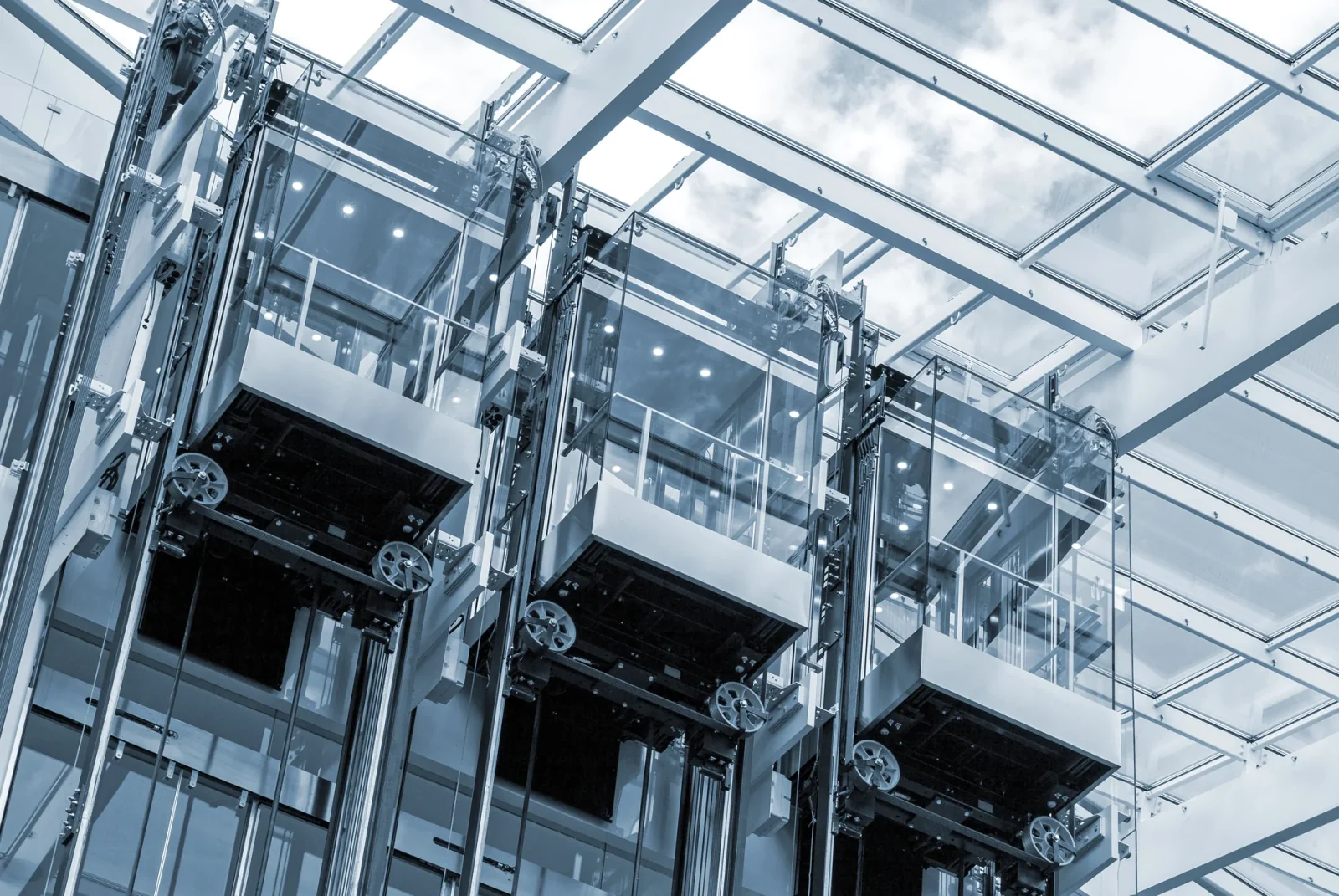 Glass elevator cars with visible car frames, pulleys and guide rails
