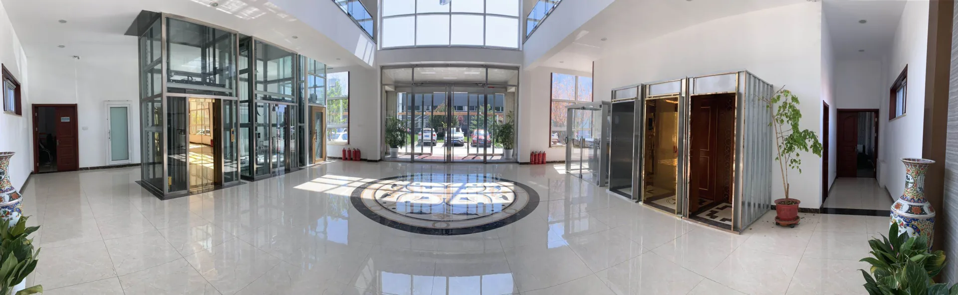 A panoramic showroom interior with glass lift displays and cabin samples.