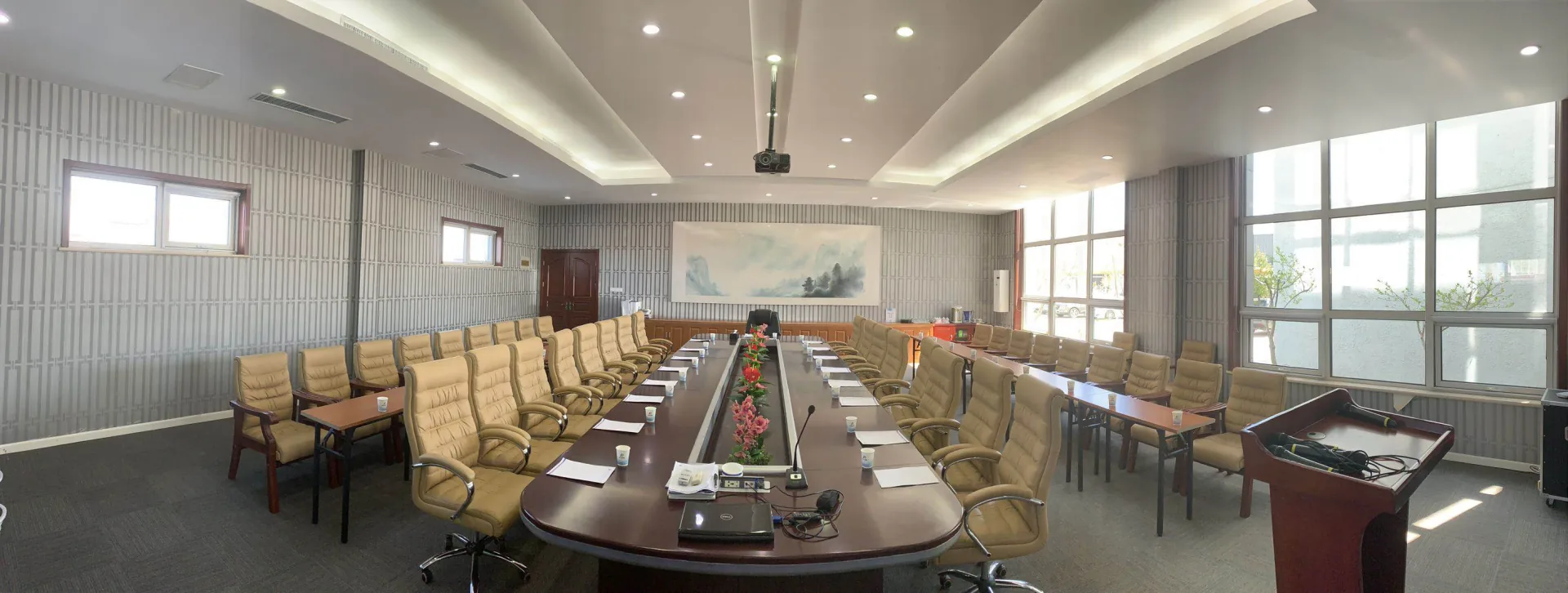 A meeting room with a long conference table, projector and seating.