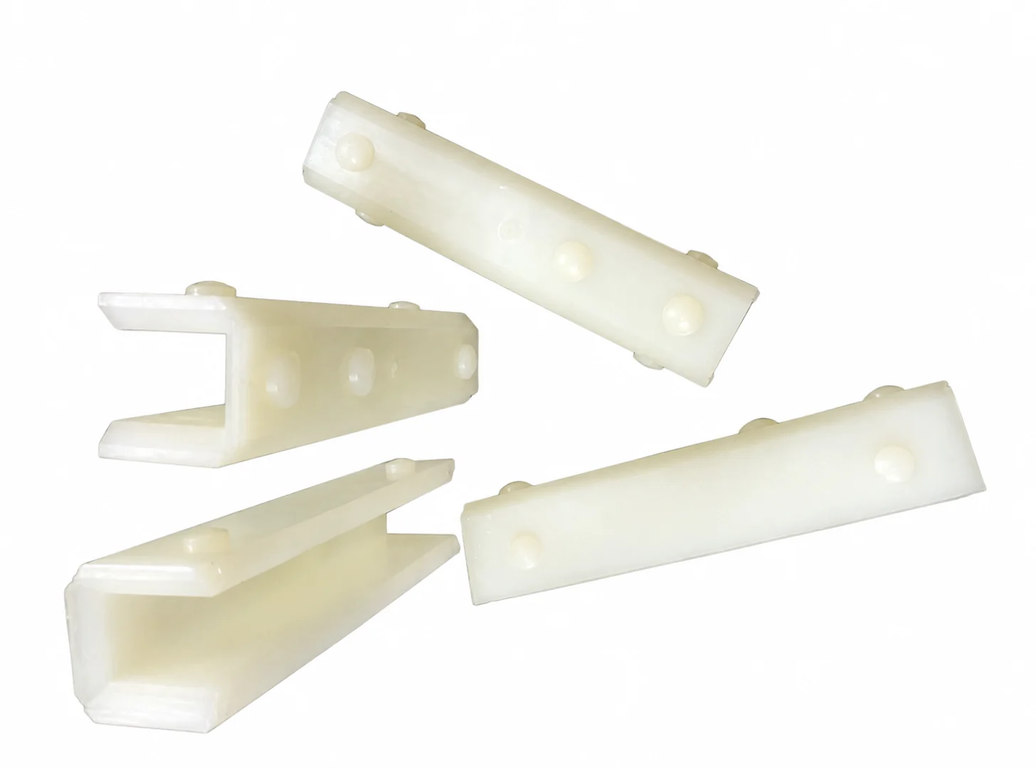 Four white U-shaped guide shoe liners on a workbench