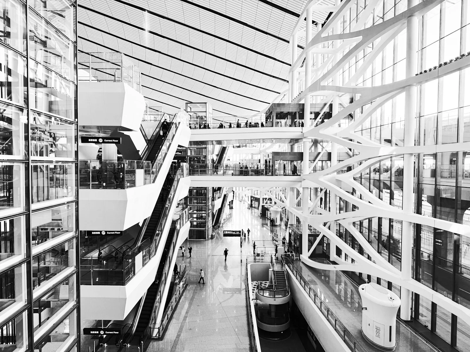 Black-and-white view of the multilevel escalator atrium at Beijing Daxing International Airport