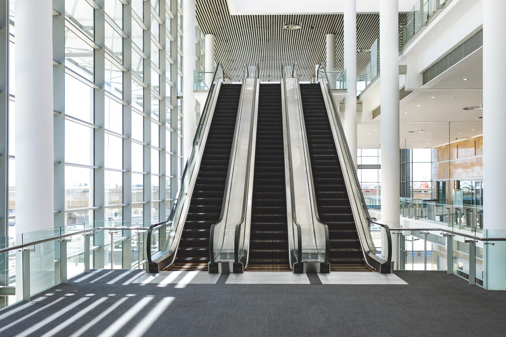 Three parallel escalators in a bright glass atrium