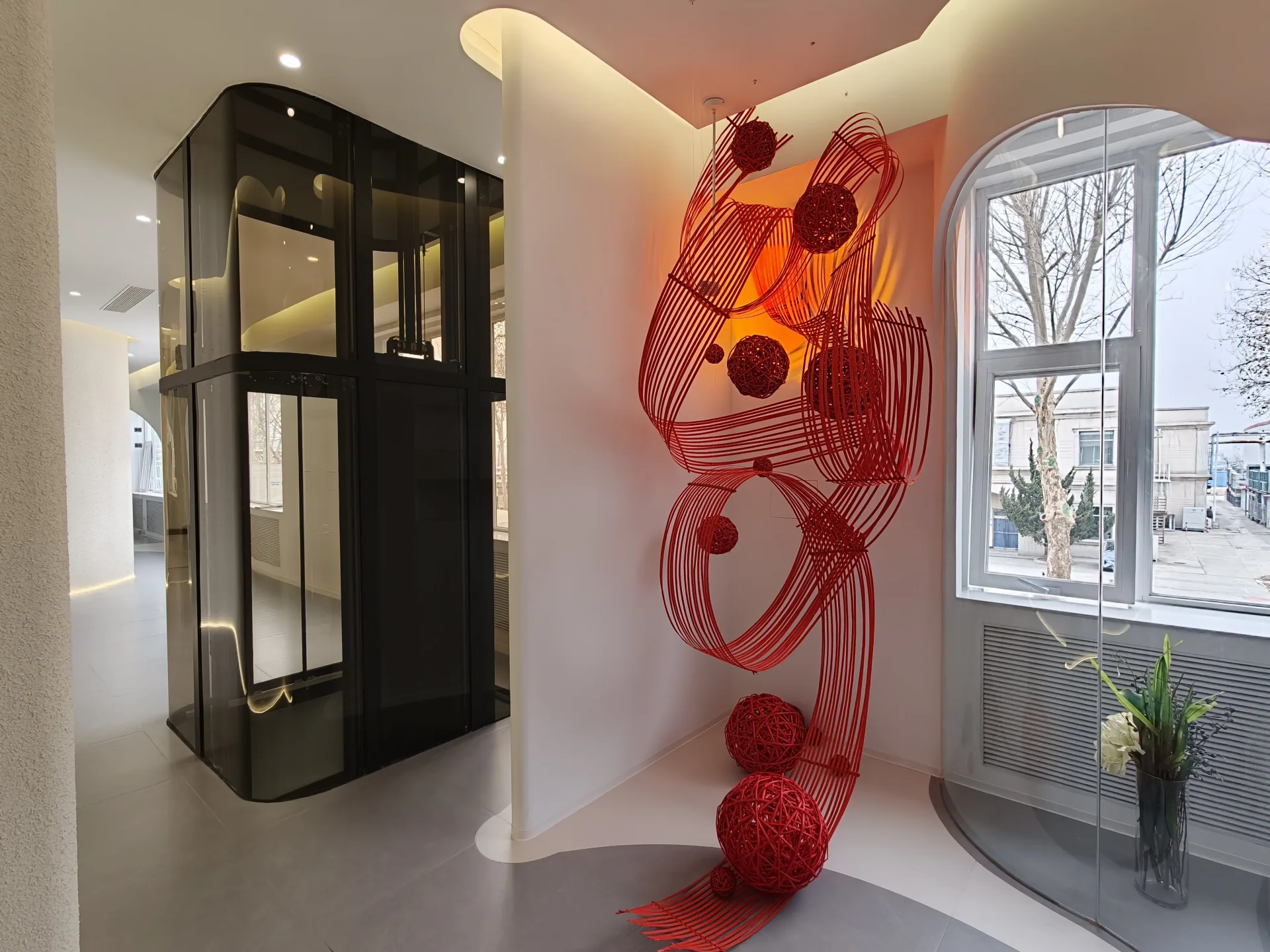 Curved-corner glass elevator showroom display with dark frame