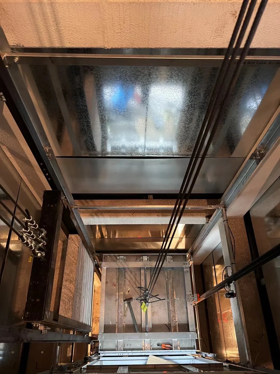 Guide rails, suspension ropes and steel supports viewed inside an elevator shaft