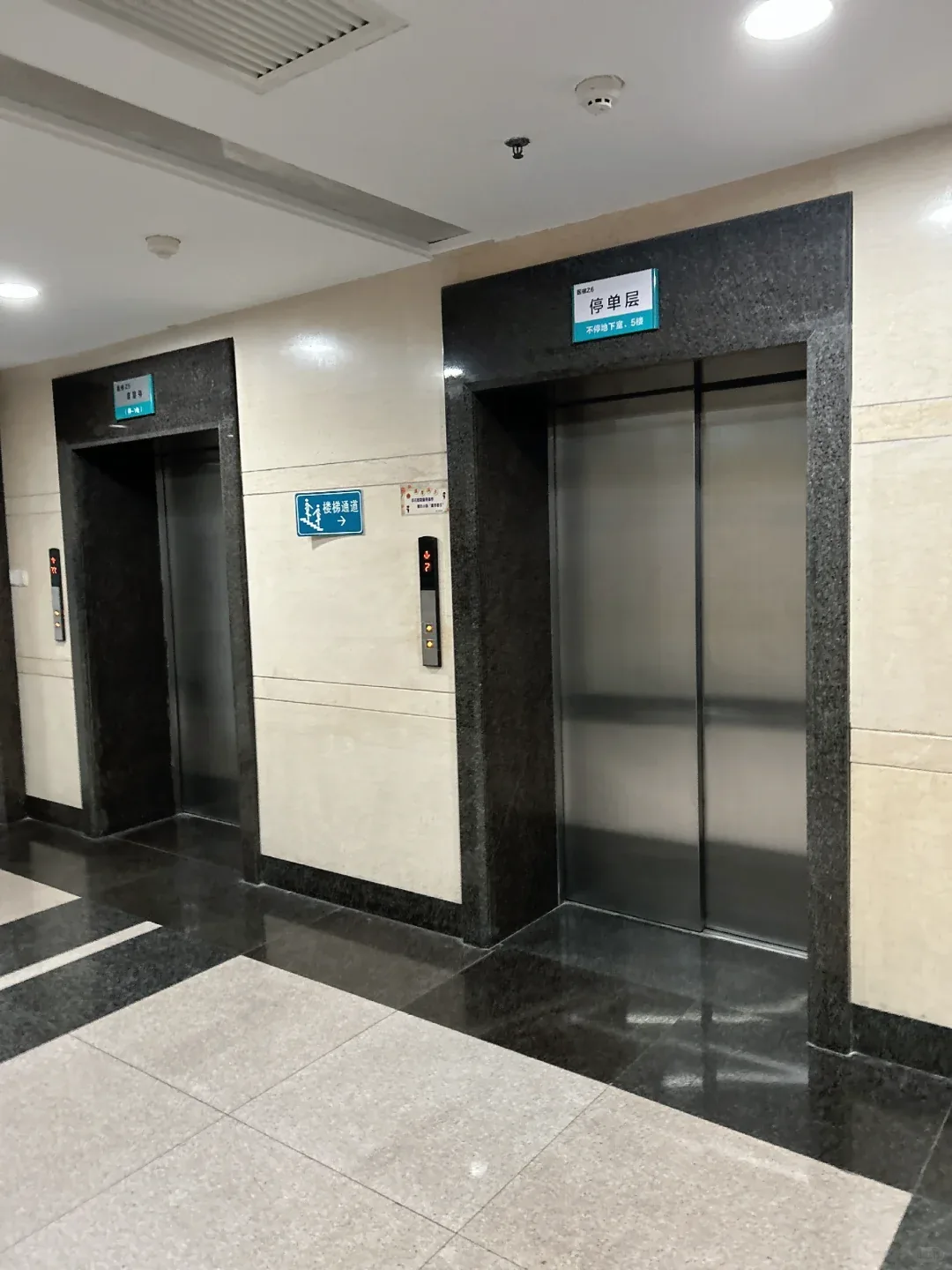 Two stainless steel elevator landing entrances with separate floor-service signs