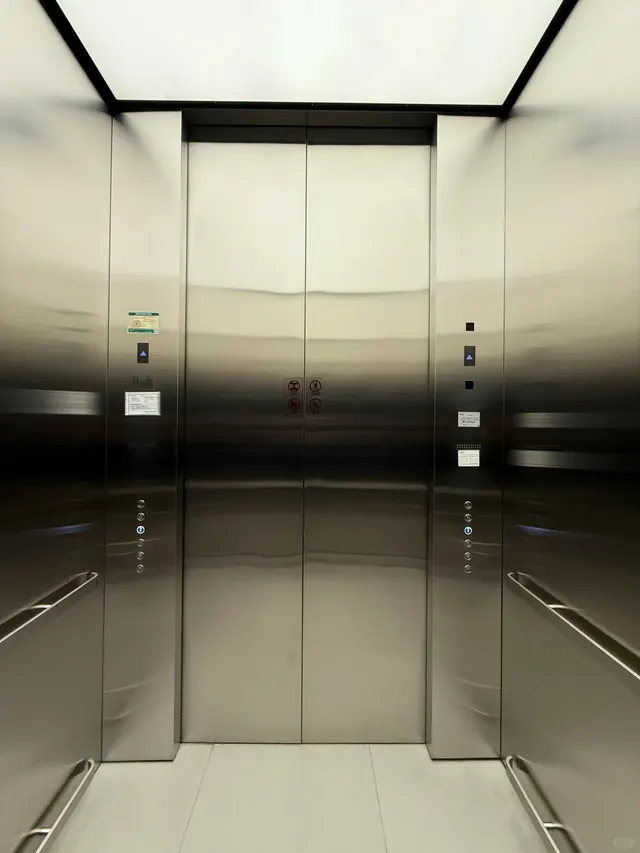 Stainless-steel passenger elevator interior with doors and control panels